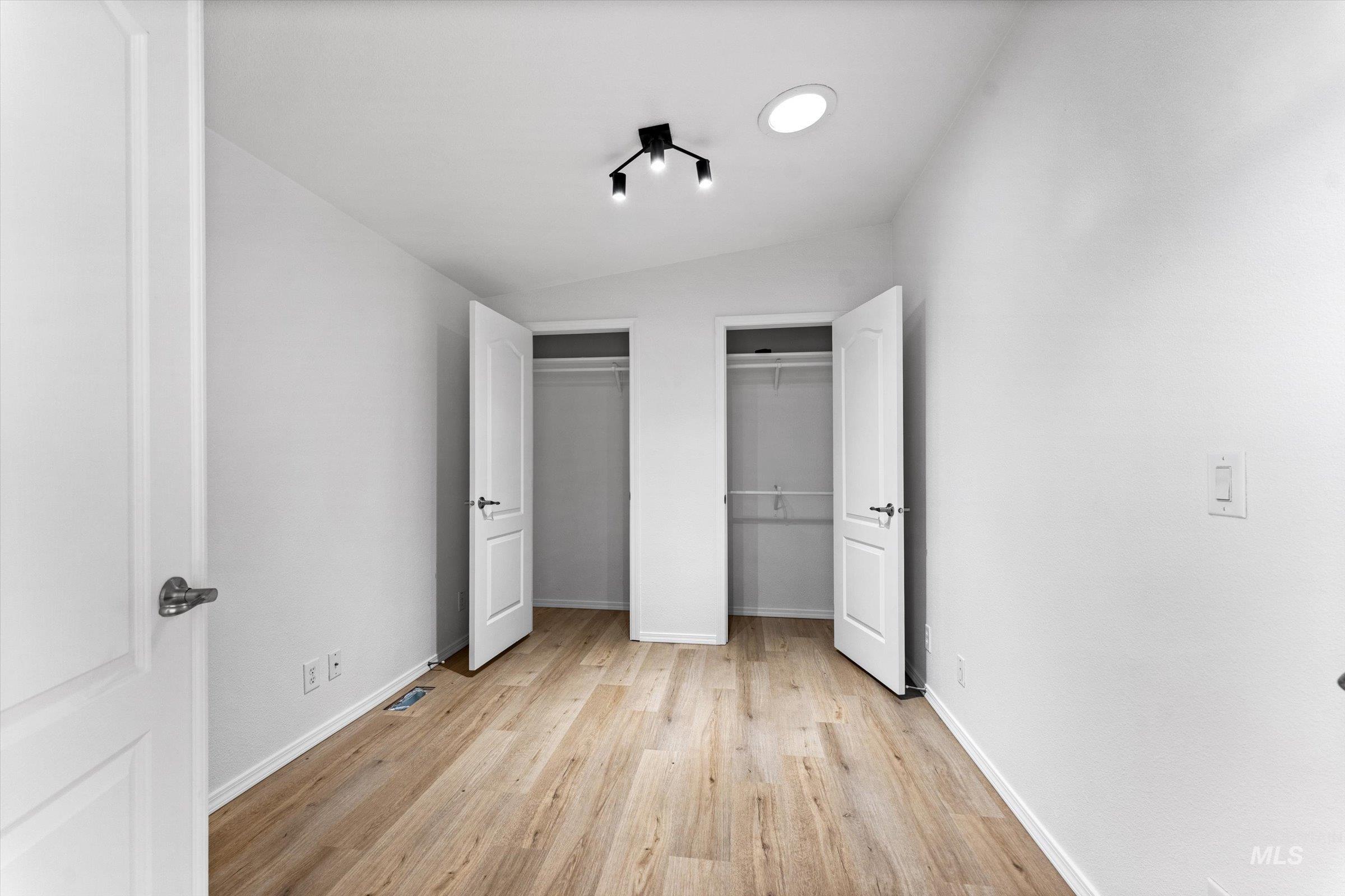 421 South Curtis Road, Unit 122 122 Boise, ID 83705 - Photo 12 of 24 Unfurnished bedroom featuring multiple closets, light wood-type flooring, and vaulted ceiling