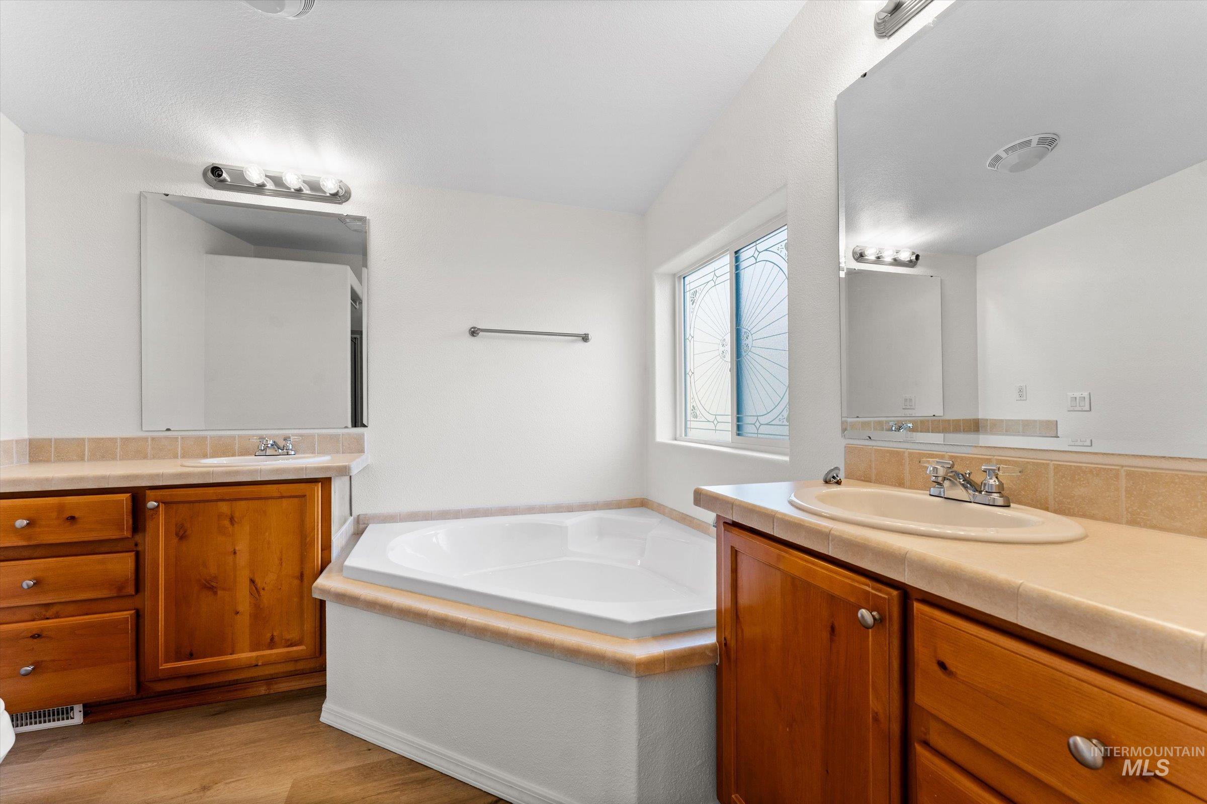 421 South Curtis Road, Unit 122 122 Boise, ID 83705 - Photo 19 of 24 Full bath featuring two vanities, a bath, light wood finished floors, and decorative backsplash