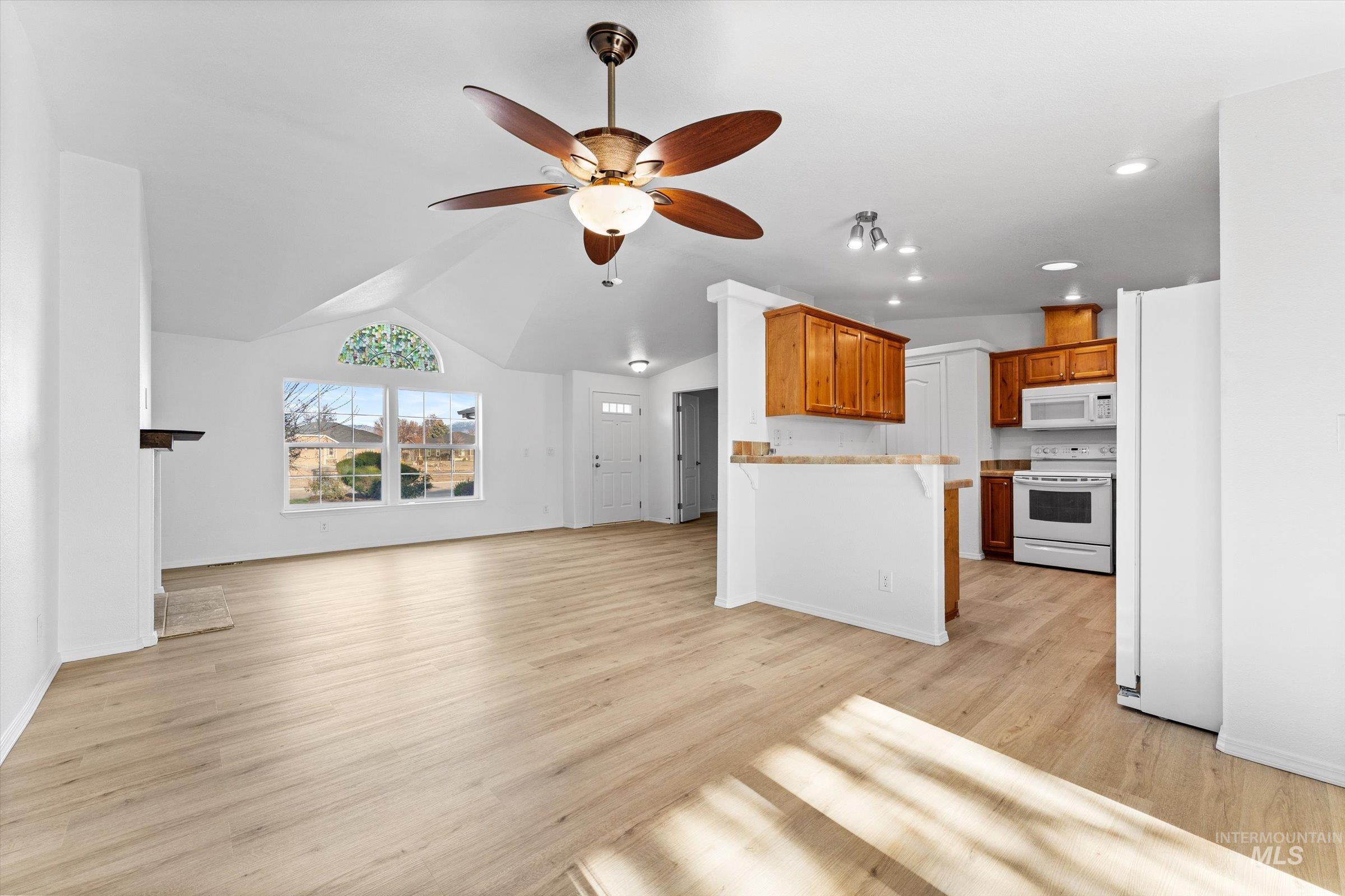 421 South Curtis Road, Unit 122 122 Boise, ID 83705 - Photo 6 of 24 Unfurnished living room featuring ceiling fan, vaulted ceiling, and light wood-style flooring
