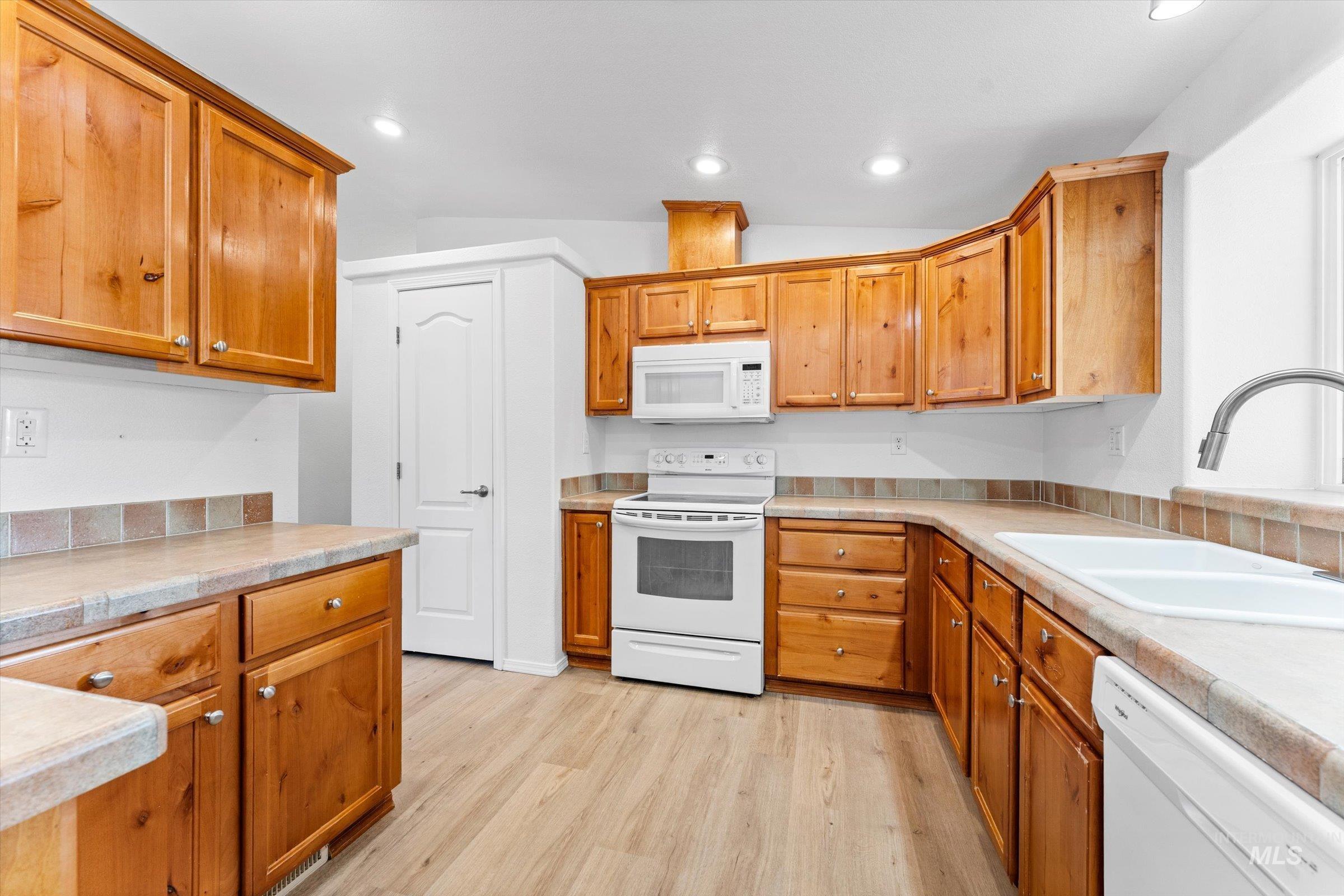 421 South Curtis Road, Unit 122 122 Boise, ID 83705 - Photo 7 of 24 Kitchen with white appliances, light countertops, light wood-type flooring, vaulted ceiling, and brown cabinets