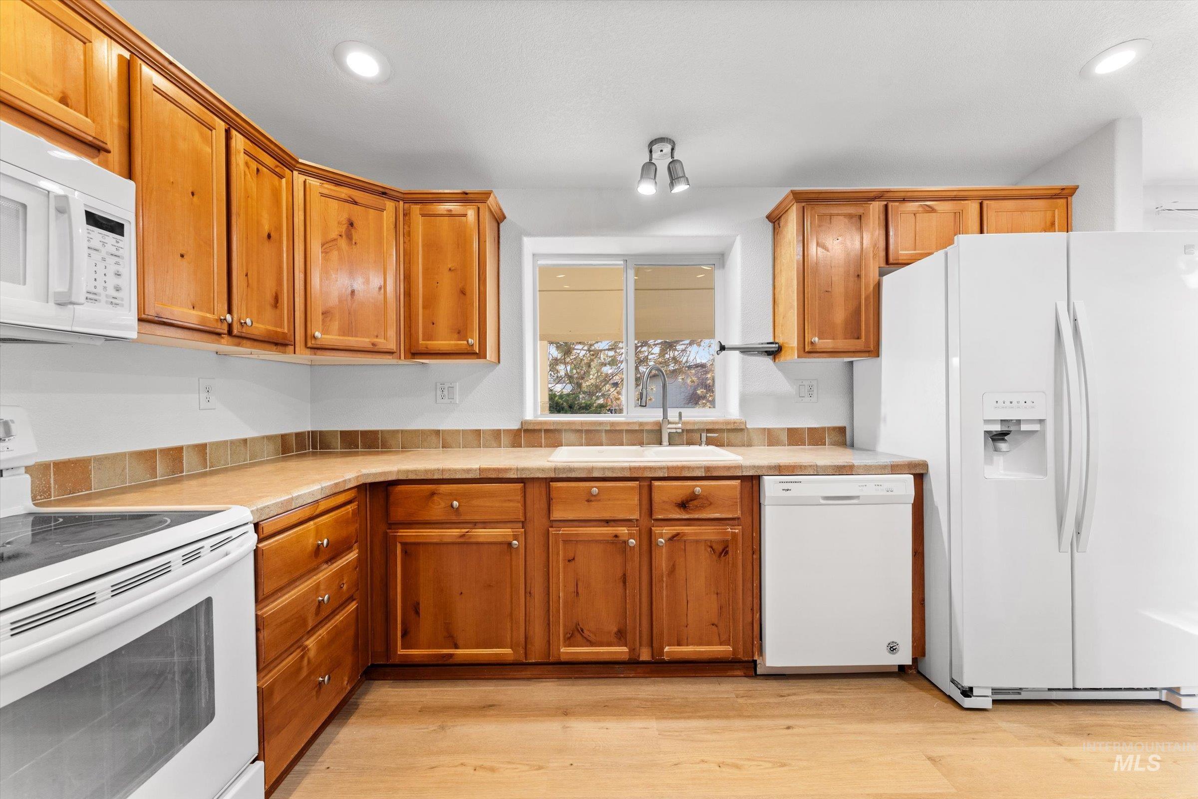 421 South Curtis Road, Unit 122 122 Boise, ID 83705 - Photo 9 of 24 Kitchen featuring white appliances, light countertops, brown cabinets, light wood-style flooring, and recessed lighting