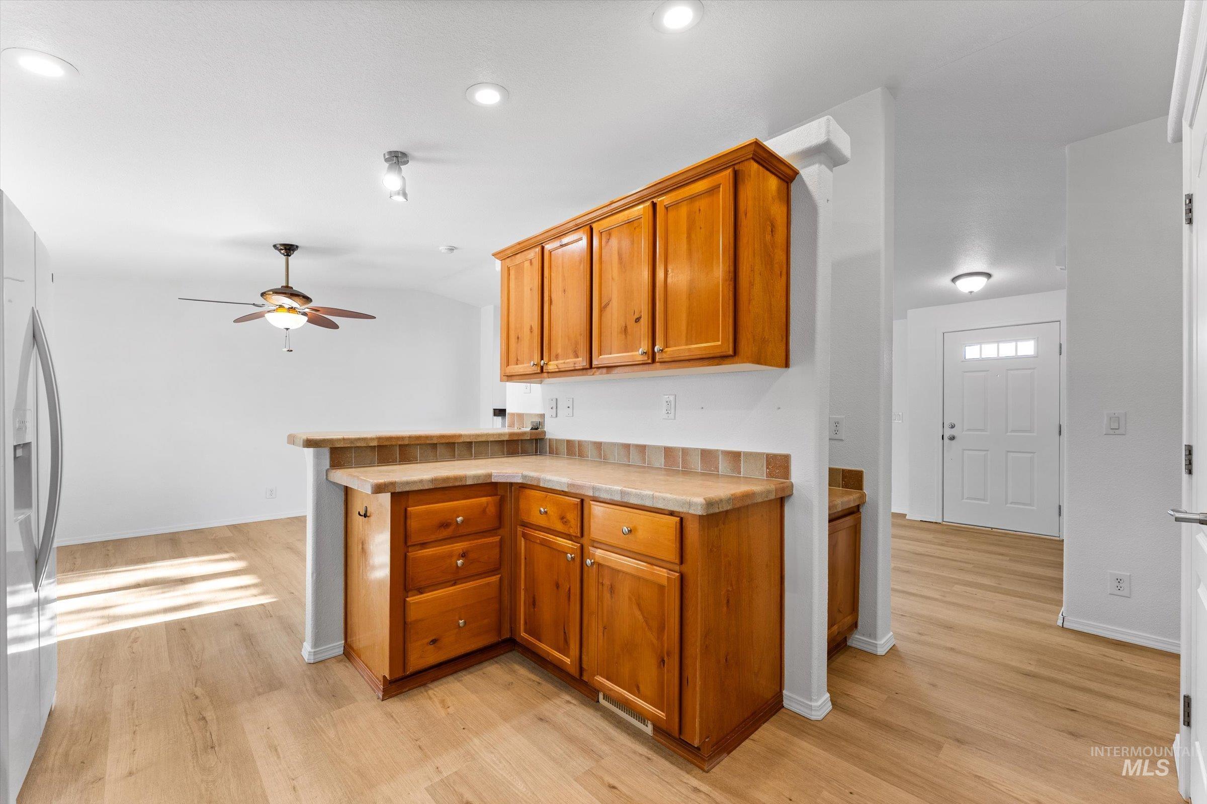 421 South Curtis Road, Unit 122 122 Boise, ID 83705 - Photo 10 of 24 Kitchen with a peninsula, brown cabinets, light countertops, and stainless steel fridge with ice dispenser