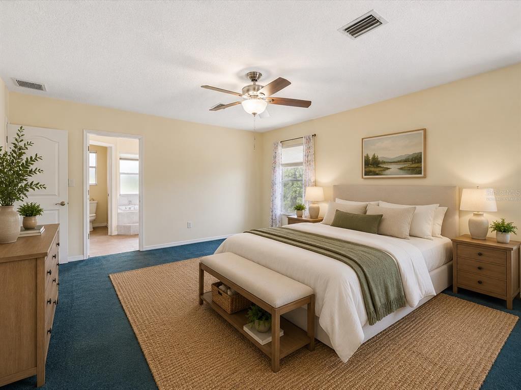 15420 Aubrey Avenue Spring Hill, FL 34610 - Photo 17 of 28 a spacious bedroom with a bed and a chandelier