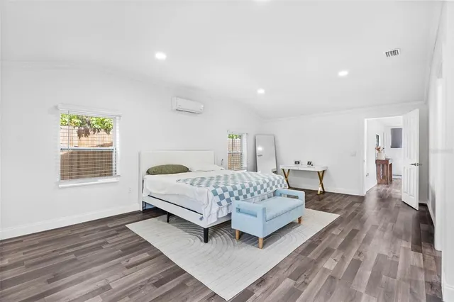 a spacious bedroom with a bed and a wooden floor