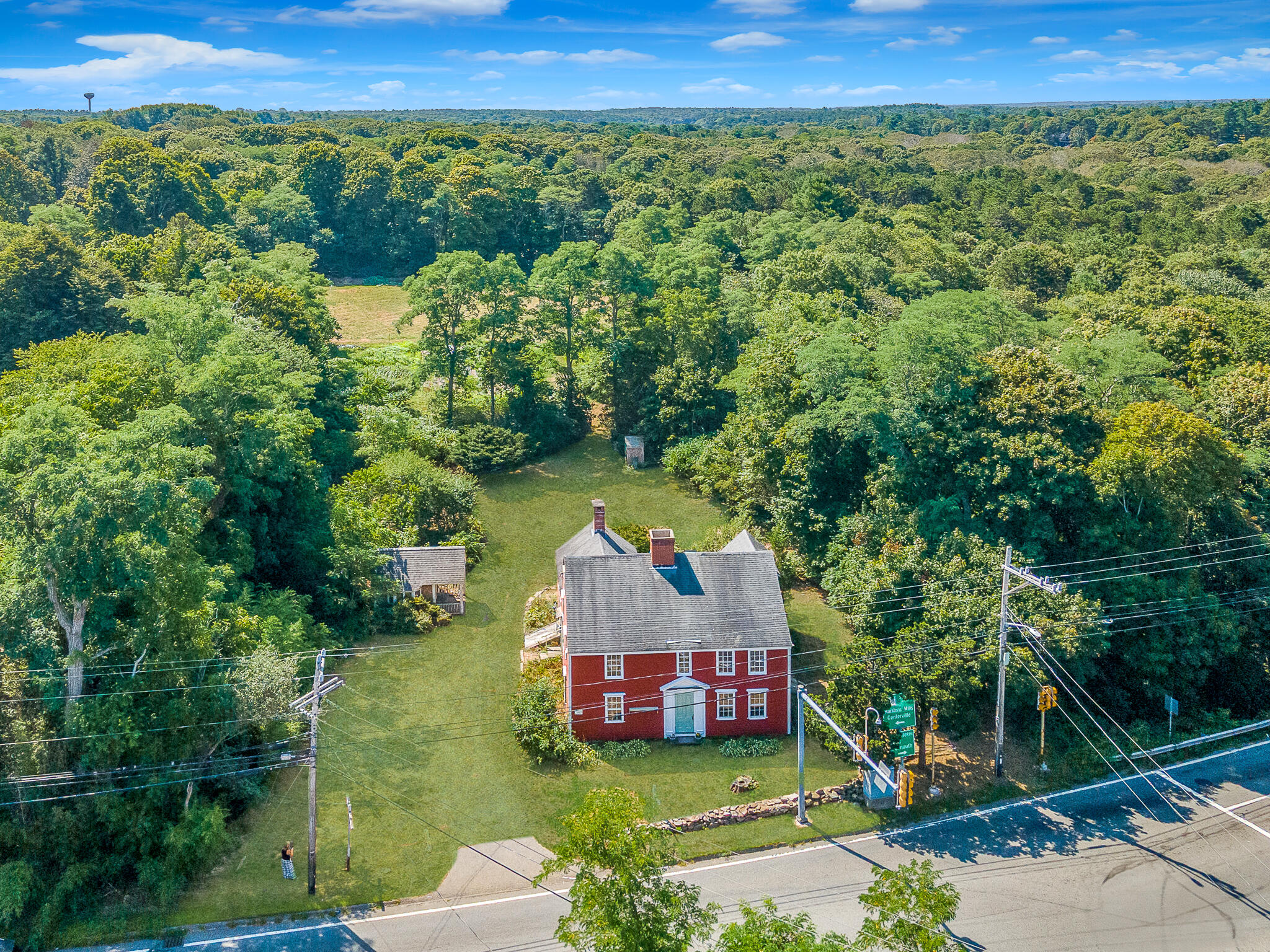 4701 Falmouth Road Cotuit, MA 02635 - Photo 9 of 39 a view of a lush green forest with a house in the background