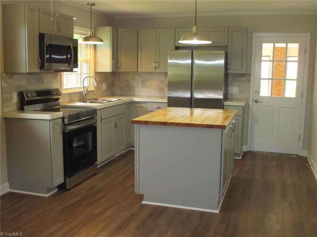 409 Price Road Lexington, NC 27295 - Photo 5 of 30 COMPLETELY NEW KITCHEN WITH HARD SURFACE COUNTERTOPS, TILE BACKSPLASH, CABINETS, ISLAND WITH DISHWASHER AND STORAGE, NEW RANGE, REFRIGERATOR AND MICROWAVE--DOOR OPENS TO BRICK SUNROOM