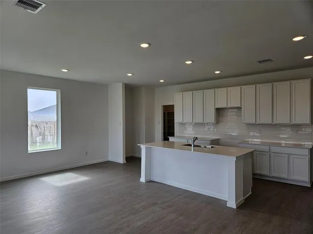 a kitchen with stainless steel appliances granite countertop a sink a stove a refrigerator a microwave oven with white cabinets