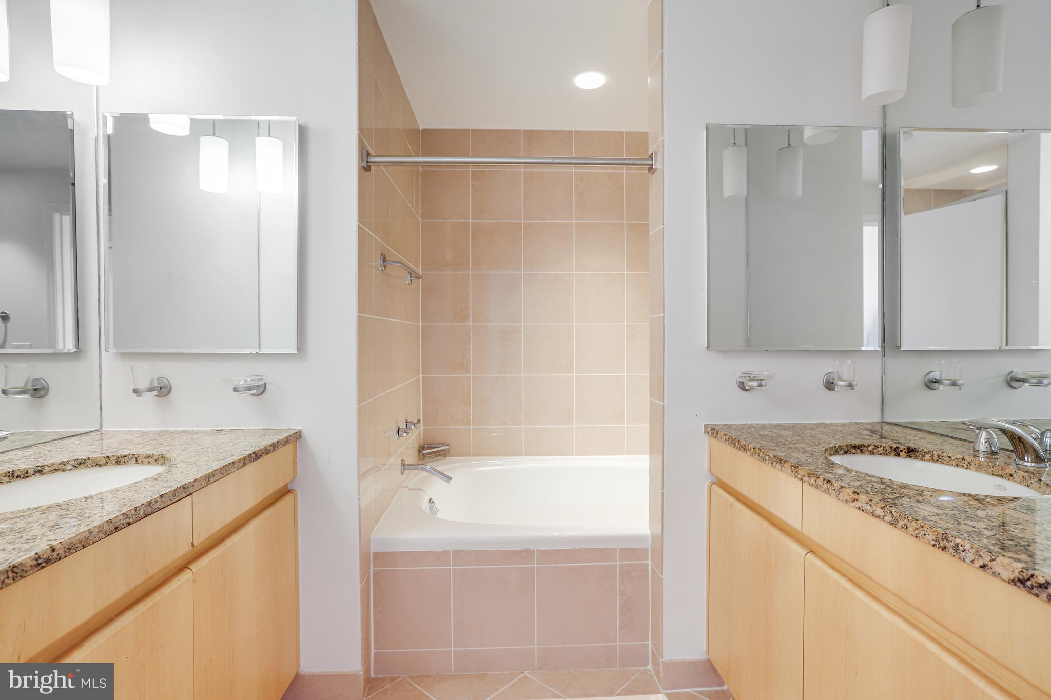 675 E Street Northwest, Unit 900 Washington, DC 20004 - Photo 12 of 40 a bathroom with a granite countertop sink a mirror and a bathtub
