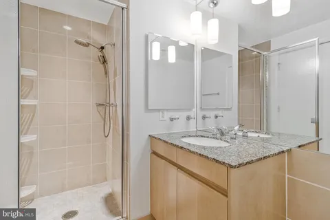 a bathroom with a granite countertop sink a shower and a mirror