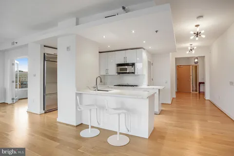a large white kitchen with a sink and chandelier