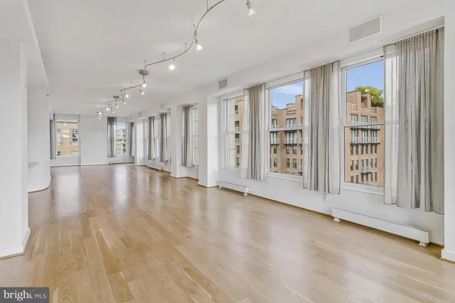 a view of an empty room with kitchen and window