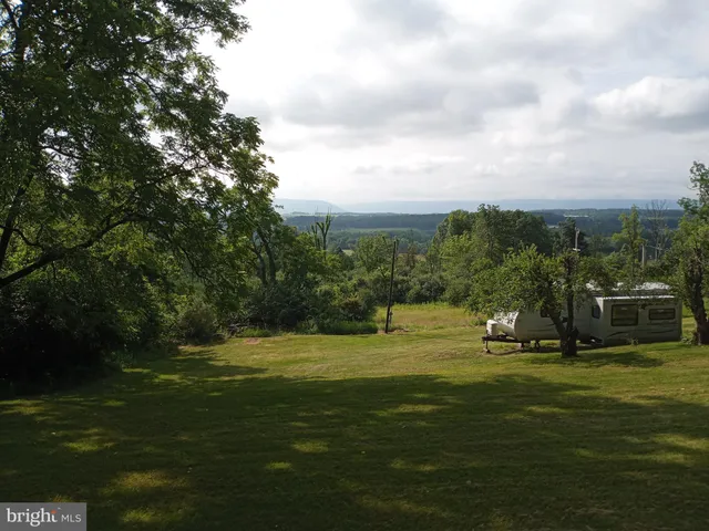 a white house with a big yard and large trees
