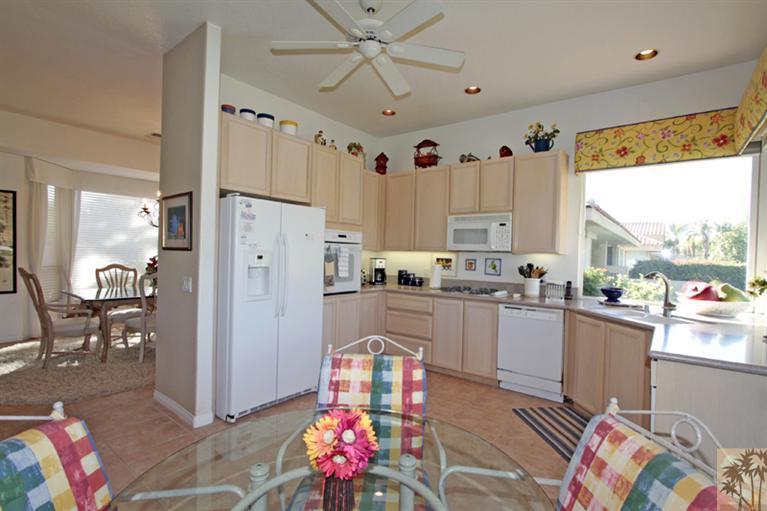 41 Augusta Drive Rancho Mirage, CA 92270 - Photo 23 of 25 a kitchen with granite countertop a white refrigerator a sink dishwasher a dining table and chairs with wooden floor