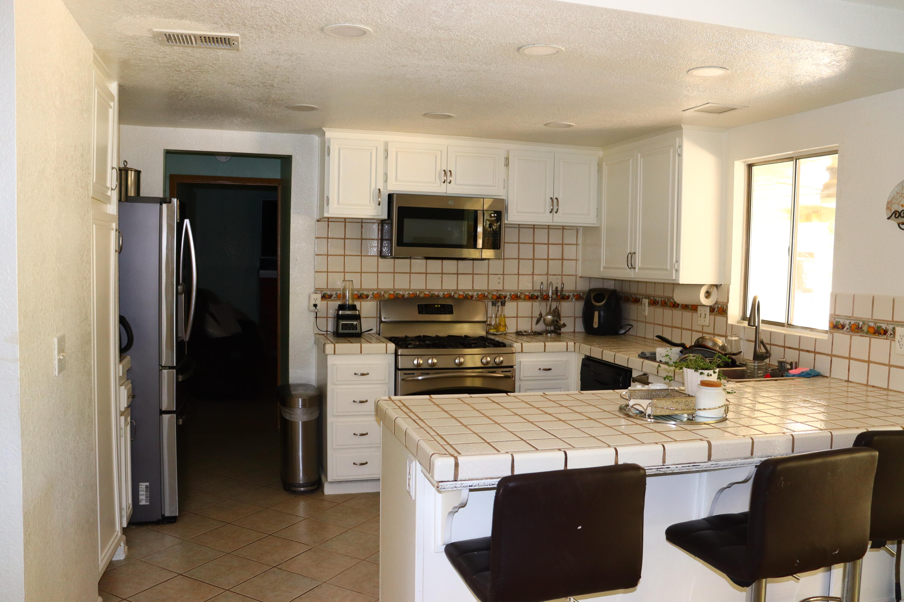 5009 East Ave R 11 Palmdale, CA 93552 - Photo 9 of 23 a kitchen with a stove a sink a microwave a refrigerator and cabinets