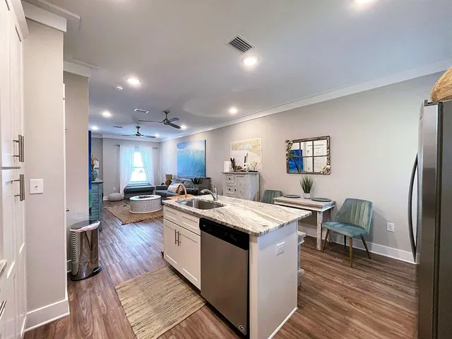 a open kitchen with stainless steel appliances granite countertop a stove oven a refrigerator a dining table and chairs with wooden floor