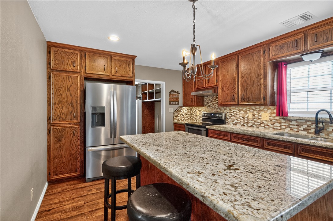 409 Ripple Creek Lane Somerville, TX 77879 - Photo 14 of 33 a kitchen with stainless steel appliances granite countertop wooden cabinets a refrigerator and a sink