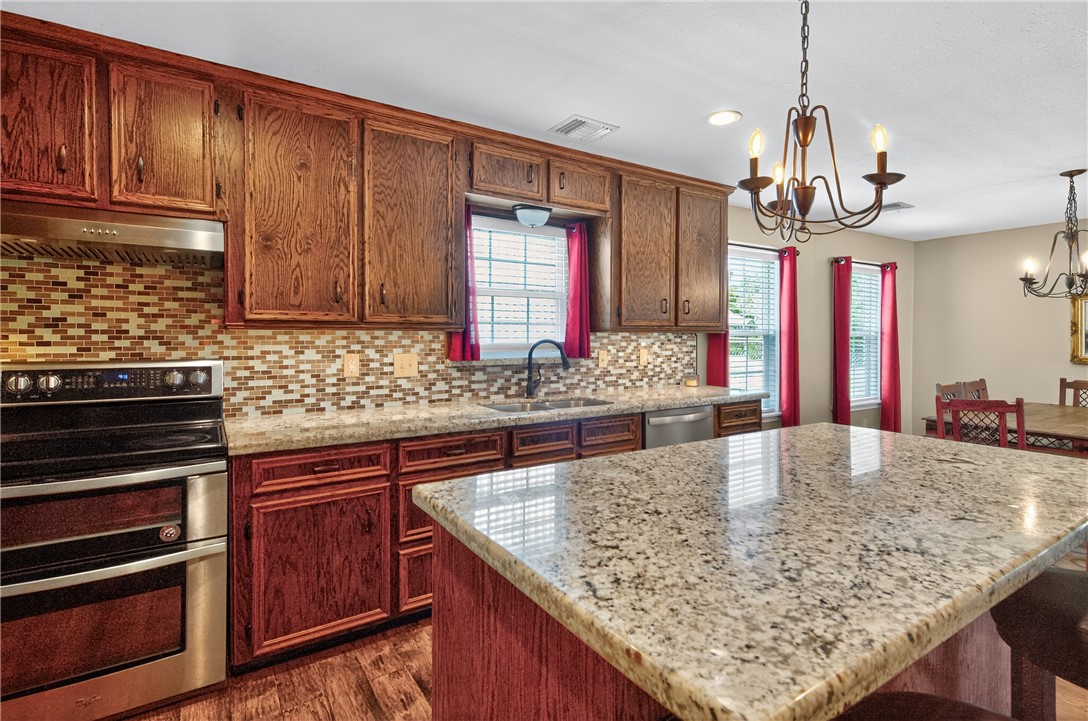 409 Ripple Creek Lane Somerville, TX 77879 - Photo 27 of 33 a kitchen with kitchen island granite countertop wooden cabinets and a stove