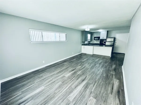 a view of kitchen and empty room with wooden floor