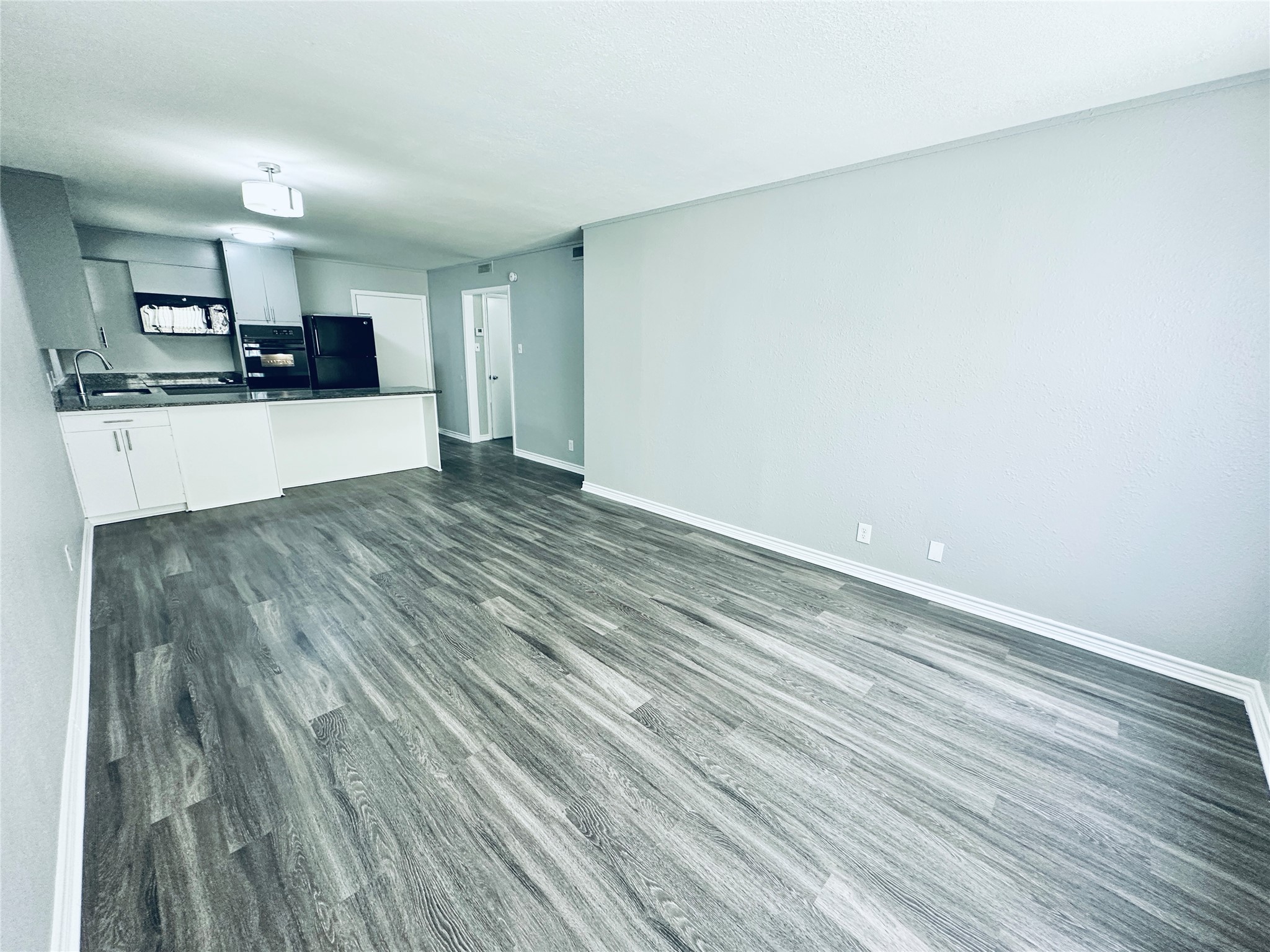 601 West 11th Street, Unit 121 Austin, TX 78701 - Photo 5 of 7 a view of kitchen and empty room with wooden floor
