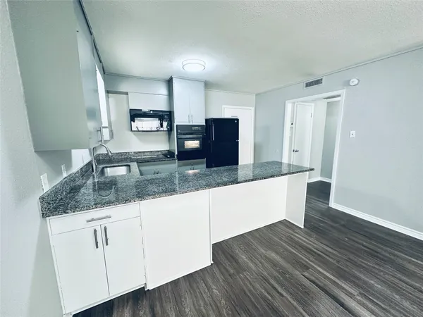 a kitchen with granite countertop a sink and cabinets