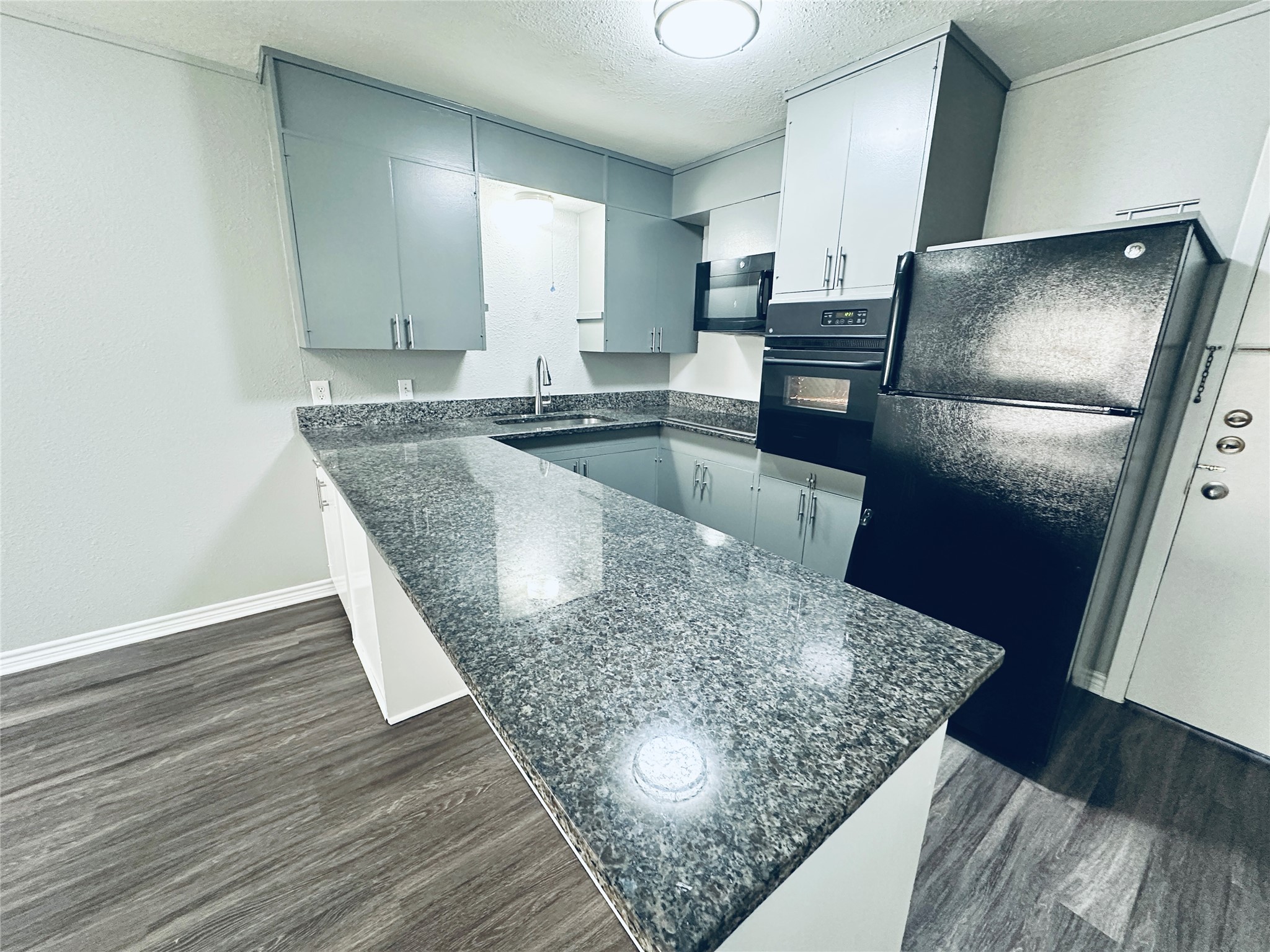 601 West 11th Street, Unit 121 Austin, TX 78701 - Photo 7 of 7 a kitchen with stainless steel appliances granite countertop a sink refrigerator and microwave