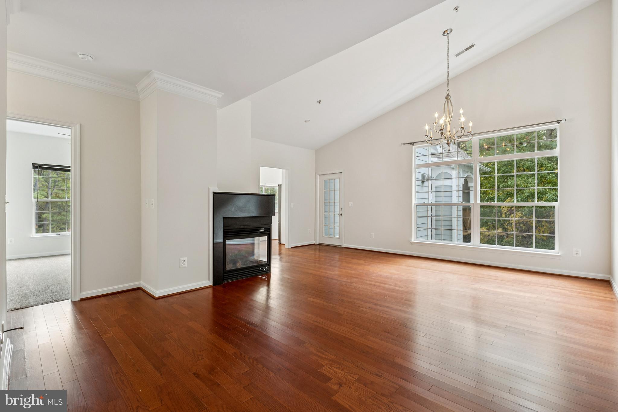 1371 Schooner Loop, Unit 1371 Solomons, MD 20688 - Photo 11 of 38 an empty room with wooden floor chandelier and windows