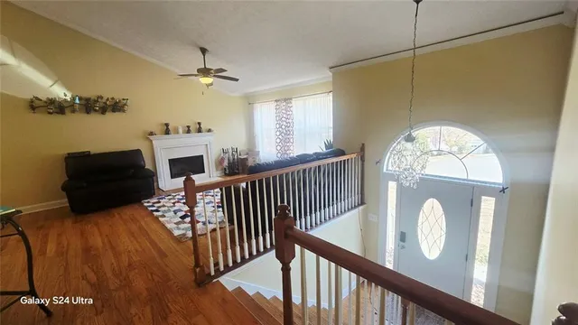 a view of a hallway with wooden floor a fireplace and a window