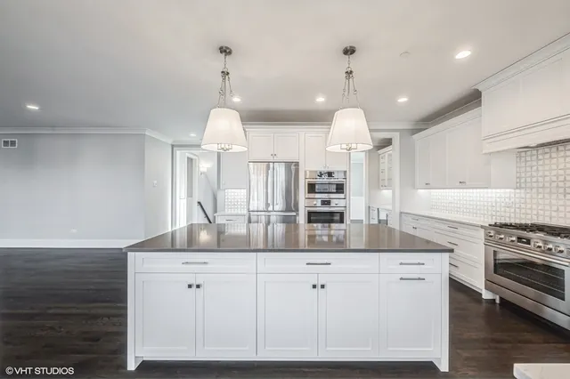 a kitchen with kitchen island white cabinets and stainless steel appliances