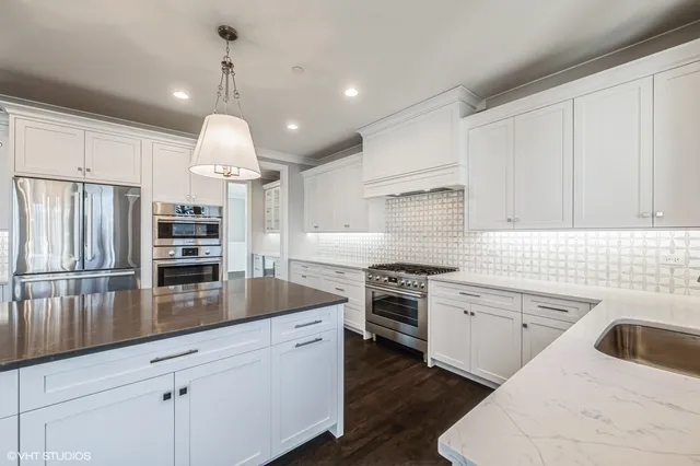 a kitchen with kitchen island granite countertop a sink stainless steel appliances and white cabinets