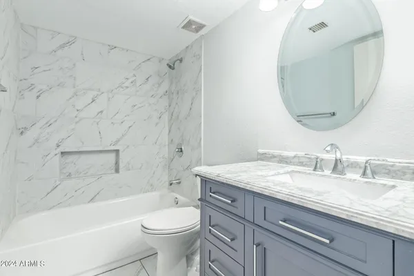 a bathroom with a granite countertop sink a toilet and bathtub