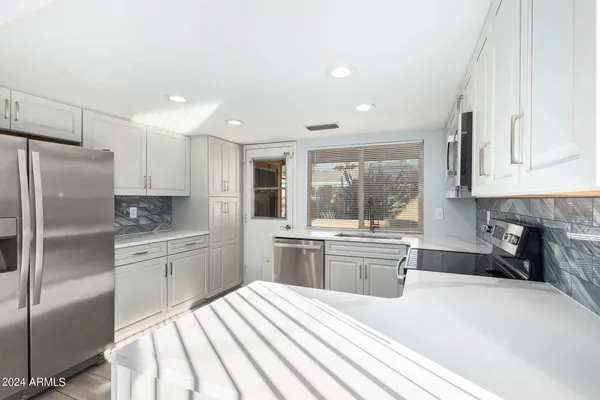 a kitchen with stainless steel appliances granite countertop a refrigerator sink and stove