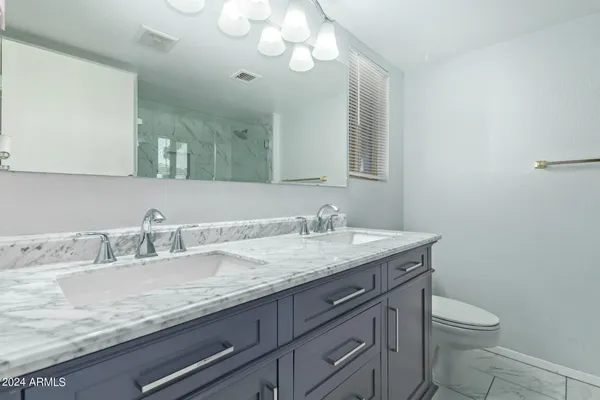 a bathroom with a granite countertop sink a toilet and a mirror