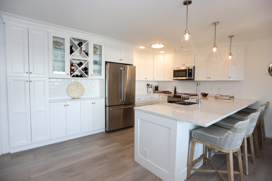 902 Ocean, Unit 906 Cape May, NJ 08204 - Photo 7 of 46 a kitchen with kitchen island a refrigerator a stove a sink and white cabinets with wooden floor