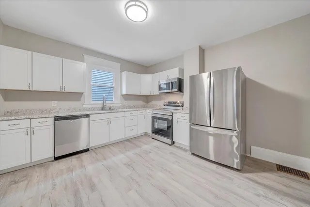 a kitchen with a refrigerator cabinets and wooden floor