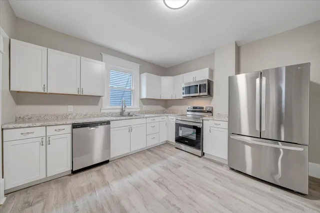 a kitchen with granite countertop white cabinets and stainless steel appliances