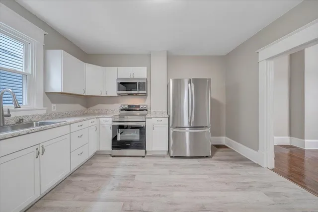 a kitchen with granite countertop a refrigerator stove and sink