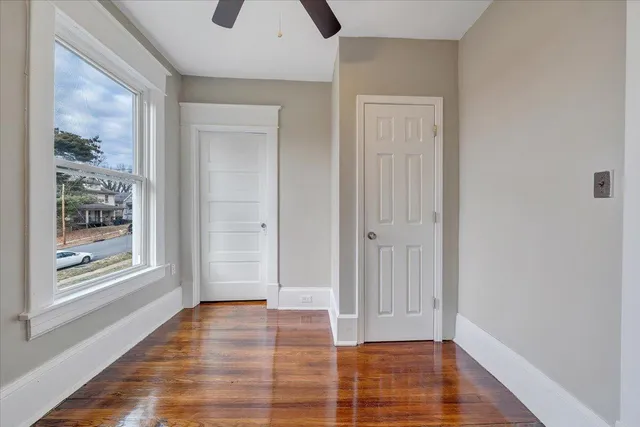 an empty room with wooden floor and windows