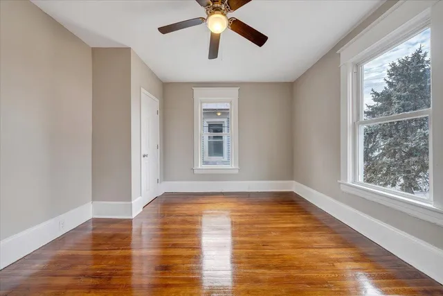a view of empty room with wooden floor and fan