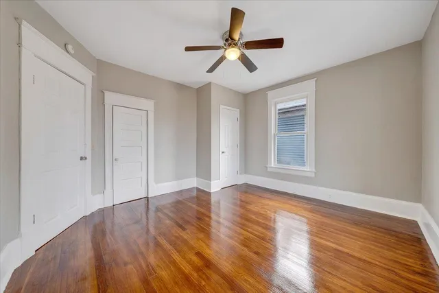 a view of an empty room with window and wooden floor