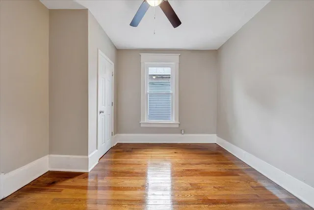 a view of empty room with wooden floor and window