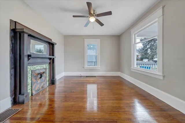 a view of empty room with wooden floor and fan