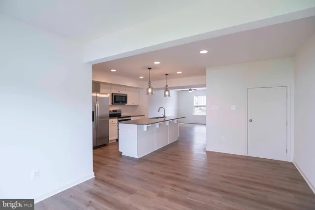 a large kitchen with kitchen island a sink dishwasher a refrigerator and a stove top oven with wooden floor