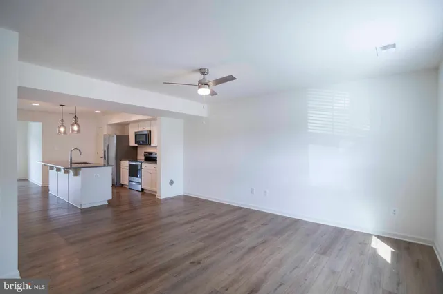 an empty room with wooden floor and a ceiling fan