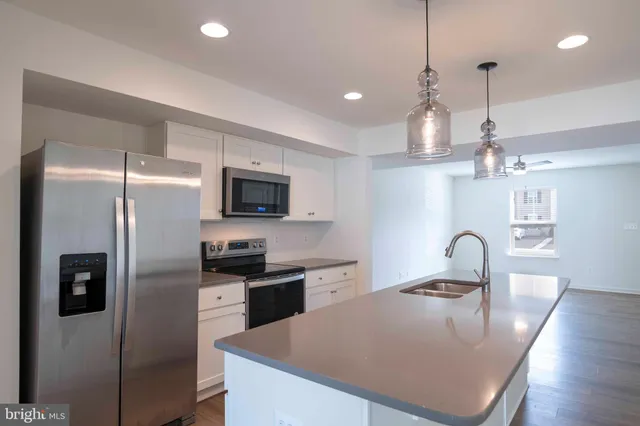 a kitchen with granite countertop a refrigerator a stove a sink a microwave a dining table and chairs with wooden floor