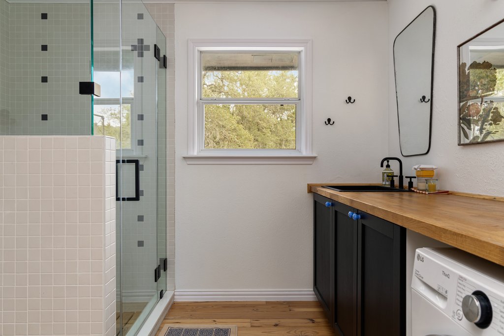 412 Rancho Grande Drive Wimberley, TX 78676 - Photo 26 of 37 Bathroom with vanity, a stall shower, washer / dryer, light wood-style floors, and healthy amount of natural light