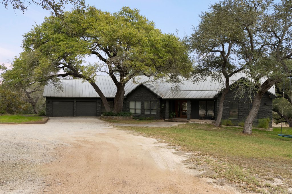 412 Rancho Grande Drive Wimberley, TX 78676 - Photo 36 of 37 View of front facade featuring driveway, a metal roof, a garage, a porch, and stone siding
