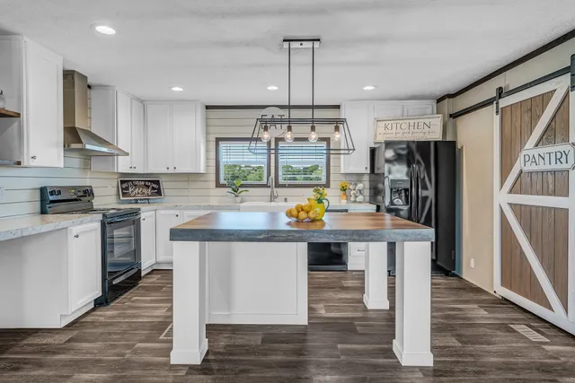 a kitchen with stainless steel appliances granite countertop a table chairs refrigerator and microwave