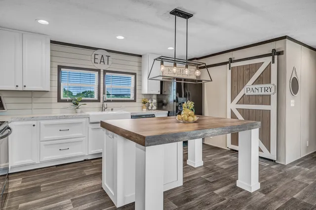 a kitchen with kitchen island granite countertop a sink appliances and cabinets