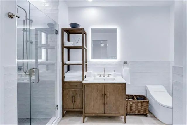 a bathroom with a double vanity sink a toilet and shower