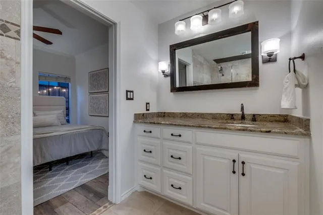a en suite bathroom with a granite countertop sink and a mirror